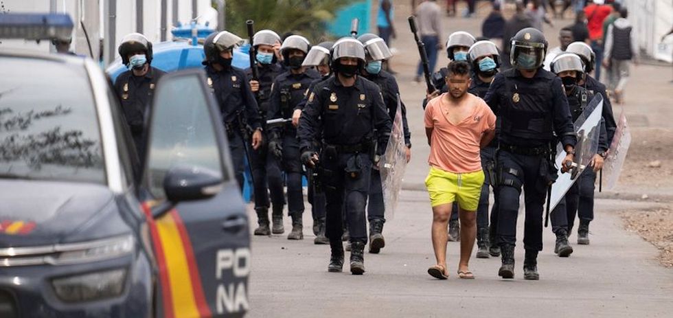 Los antidisturbios trasladan a un detenido tras los altercados ocurridos en el campamento  (Tenerife). EFE