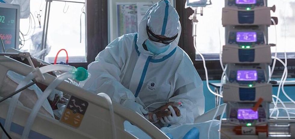 Sanitario de la UCI ay&uacute;dando a un paciente. EFE