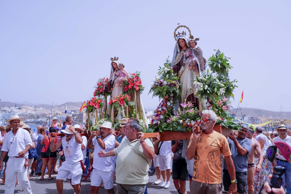 Las dos imágenes se presentan hacia una tercera imagen de la Virgen en el muelle de Arguineguín, portadas por marineros y vecinos, entre estos el concejal de Pesca