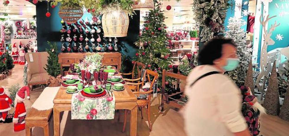 Una mujer pasa por delante de un establecimiento comercial decorado con una mesa de celebración preparada con los tradicionales motivos navideños. / LUIS TEJIDO / EFE